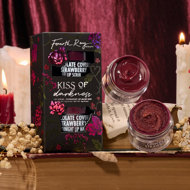 Kiss of Darkness ColourPop Lip Care Kit showcasing Fourth Ray Beauty duo - Chocolate Covered Strawberry lip scrub and overnight lip mask - opened in glass jars beside the floral black box, styled on vintage books with candles and dried flowers.