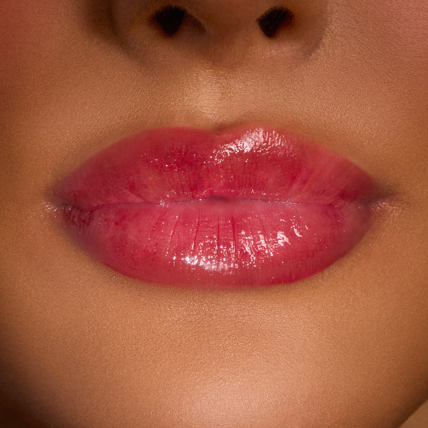 Glossy lips wearing ColourPop Merry Grinchmas Swirl Lip Gloss Kit, displaying a sheer pink-red swirl tint with high shine and a smooth, cushiony finish in a tight studio close-up for holiday lip color.