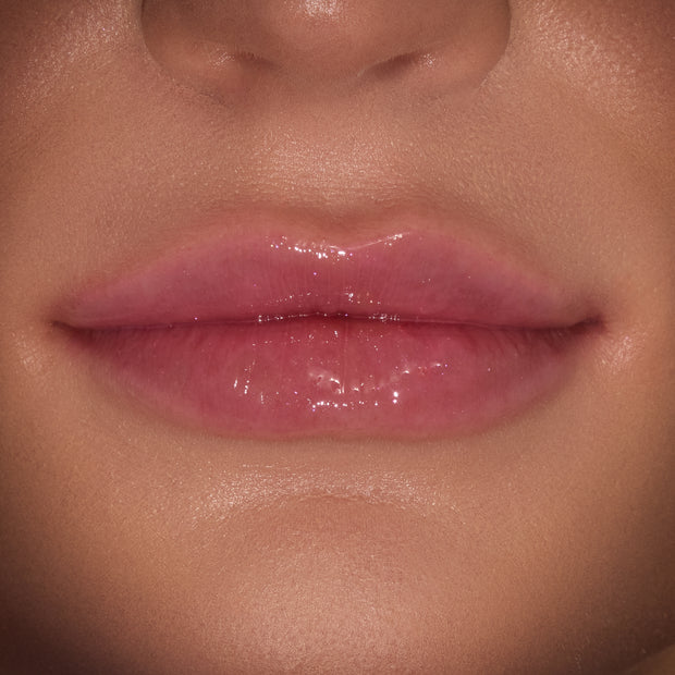 Glossy lips wearing a sheer pink, high-shine finish from the ColourPop Merry Grinchmas Swirl Lip Gloss Kit, shown in a tight close-up to highlight the glassy sheen and smooth texture.