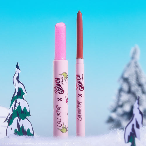 Colourpop Pinky Who So Juicy Plumping Gloss Stick stands uncapped beside a coordinating lip liner, revealing a glittery pink bullet; both in The Grinch x ColourPop pink tubes, set in a snowy pastel-blue holiday scene with cartoon trees.
