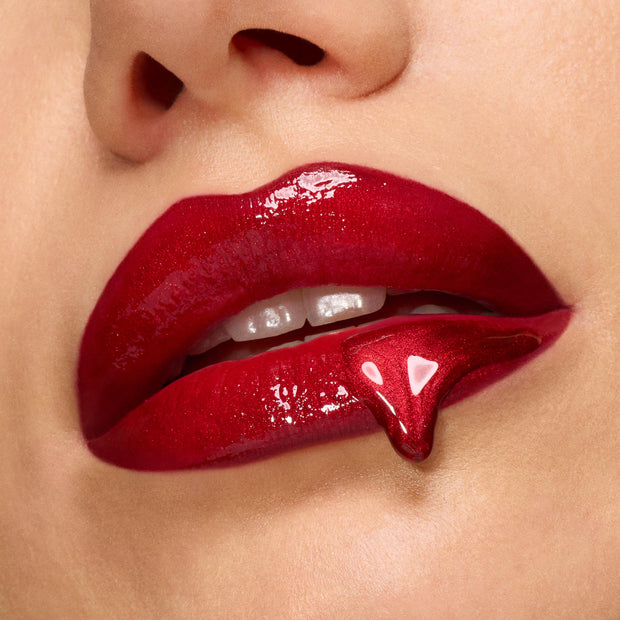 Glossy deep-red lips showcase high-shine lip gloss with a fang-shaped drip, spotlighting the Twilight New Moon x ColourPop Full Collection Set, a ColourPop Full Collection Set inspired by vampy glamour.