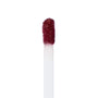 Doe-foot applicator coated with ColourPop LAX Ultra Matte Lip, a deep burgundy liquid lipstick, depositing pigment in a clean macro close-up against a white studio background.