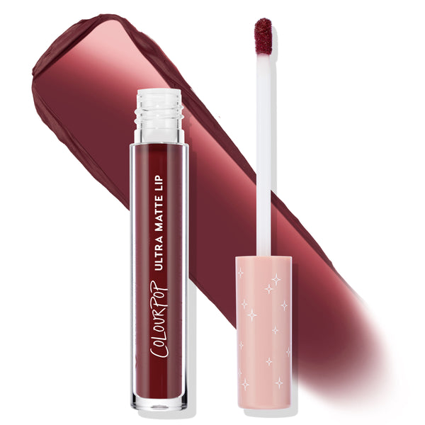ColourPop LAX Ultra Matte Lip liquid lipstick with clear tube and white logo, deep oxblood shade, shown open with doe-foot applicator and blush pink star-print cap beside a broad matte burgundy swatch on white background.