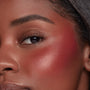 ColourPop Liquid Blush Royal Flush applied on a model’s cheek, rosy-red pigment blended from apple to temple with a dewy, luminous finish, close-up showcasing smooth, even payoff beside the eye.