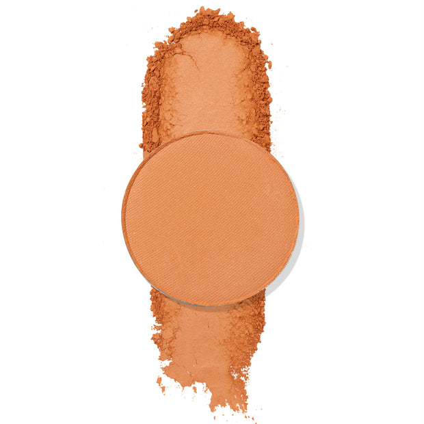 Laguna ColourPop Pressed Powder Shadow pan resting on a vertical swipe of crushed pigment, showcasing a warm matte terracotta-orange shade in a single round refill, swatched on a white background for color payoff.