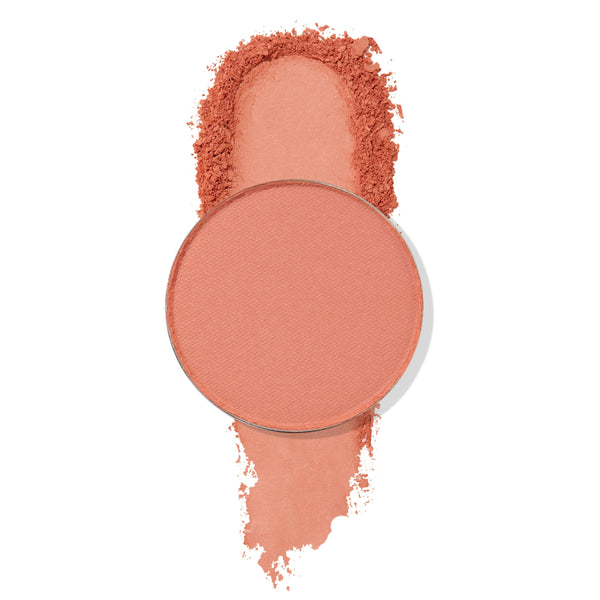 ColourPop Lay Low pressed powder shadow pan sits atop a wide coral-peach matte swatch with softly crushed edges, showcasing the pigment and fine texture against a clean white background.