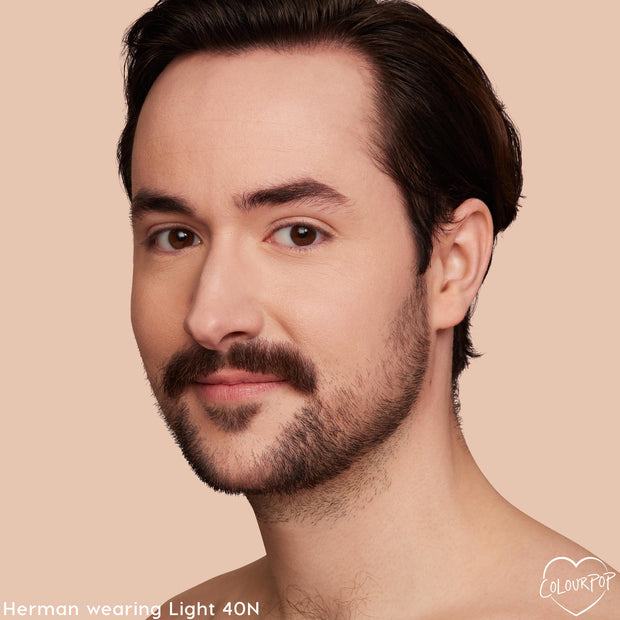Model wearing Light 40 N, a ColourPop Hyaluronic Hydrating Foundation shade, showcases smooth, natural medium coverage with a hydrated finish; close-up face with mustache and stubble against a soft beige background.