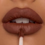 Full lips apply Espresso Martini Ultra Blotted Lip with a doe-foot applicator, revealing a soft-matte, blurred finish in a rich cocoa-brown shade; close-up of ColourPop Ultra Blotted Lip on warm skin.