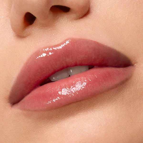 Glossy, hydrated lips showcase Kiss of Darkness from the ColourPop Lip Care Kit, delivering a high-shine, soft pink finish in a macro close-up against smooth, natural skin.