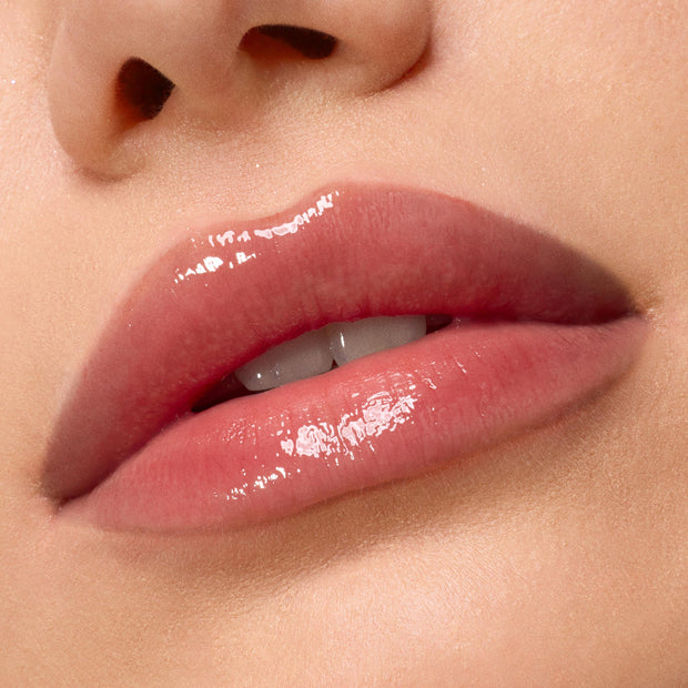 Glossy, hydrated lips showcase Kiss of Darkness from the ColourPop Lip Care Kit, delivering a high-shine, soft pink finish in a macro close-up against smooth, natural skin.