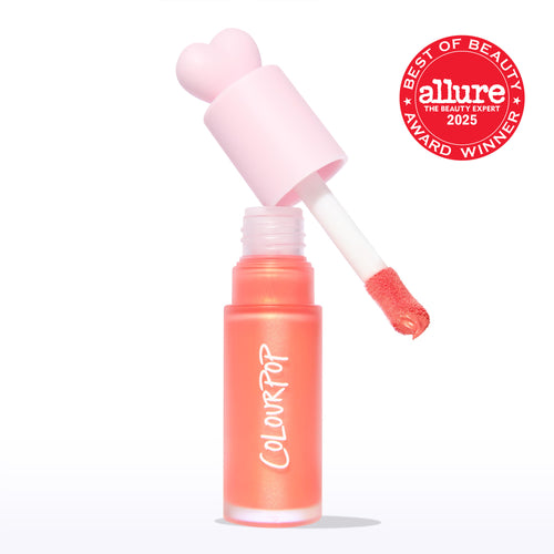 ColourPop Liquid Blush in Perfect Peach, doe-foot applicator lifting from a frosted coral tube with a pink heart-shaped cap, revealing a warm peachy tint; Allure 2025 Best of Beauty badge on a clean white background.