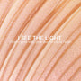 I See the Light ColourPop Liquid Highlighter swatched in sweeping ridges, showing a warm gold base with pink duochrome shimmer; creamy liquid texture gleams under light in a close-up macro for a luminous glow.