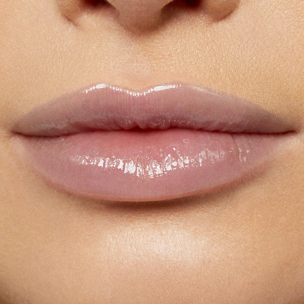 Glossy lips wearing Team Edward Lux Lip Oil reflect a high-shine, sheer pink finish, captured in a studio close-up to showcase the smooth, hydrated look of ColourPop Lux Lip Oil on natural lips.