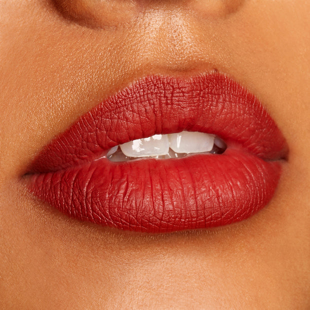 Full lips lightly parted, lined and filled with Love Bug ColourPop Lippie Pencil, showcasing a rich terracotta-red matte finish with crisp edges in a tight studio close-up highlighting smooth pigment and defined lip contour.