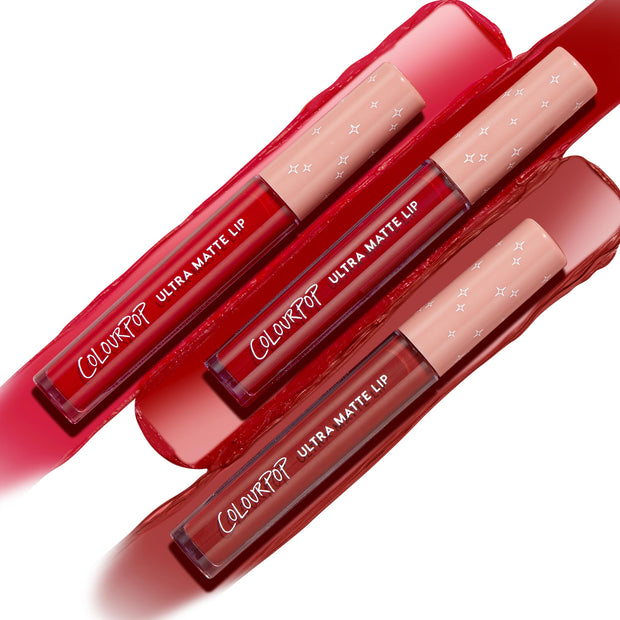 Three ColourPop Ultra Matte Lip tubes from the Major Hottie set showcase bold red and berry liquid lipstick shades, laid diagonally across glossy matching swatches; clear barrels with white logos and peach caps with star prints emphasize the ultra matte finish.