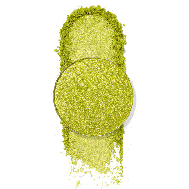 Mary Jane ColourPop Pressed Powder Shadow pan showcases a bright lime-green metallic shade with gold shimmer, shown crushed and swatched with loose pigment around the round pan on a white background to highlight sparkle and payoff.