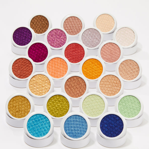 Obvi ColourPop Super Shock Shadow displays its shimmery, scale-textured pan, shown open amid a rainbow of Super Shock Shadow singles in white round pots, arranged tightly on a clean white background.