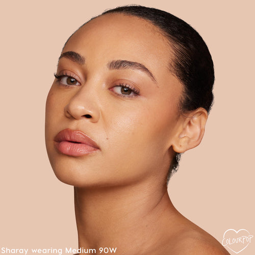 ColourPop Pretty Fresh Creamy Concealer in Medium 90W perfects a model’s complexion, showing smooth, natural coverage under the eyes and cheeks; a studio close-up on a beige backdrop highlights the warm medium shade’s skin-like finish.