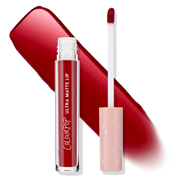 Melonade shade of ColourPop Ultra Matte Lip stands open with a doe‑foot applicator and clear tube, showing a bold deep red pigment; a sweeping red swatch behind and a blush‑pink cap with white stars on a clean white background.