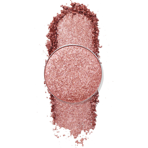 ColourPop Misty Pressed Powder Shadow pan, a shimmery rose-gold shade, shown crushed and swatched in a vertical streak, metallic glitter catching light, single refill pan on a clean white background.
