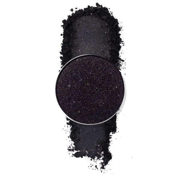 ColourPop Nightdream pressed powder shadow pan showcasing a deep black‑purple eyeshadow packed with fine multicolor sparkle, displayed with a crushed swatch on a white background, highlighting its glittery smoky finish.