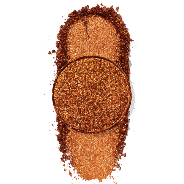 Not Ok ColourPop Pressed Powder Shadow pan in metallic copper, its crushed pigment smeared in an oval swatch on a white background, highlighting dense shimmer, warm undertones, and sparkling texture.