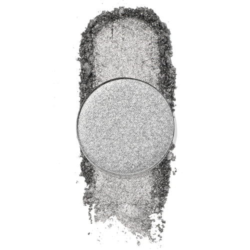 On a Whimsy pressed powder shadow by ColourPop, a cool-toned metallic silver single pan, catching light as the shade is swatched in a dense shimmer trail with loose glittery pigment on a white background.