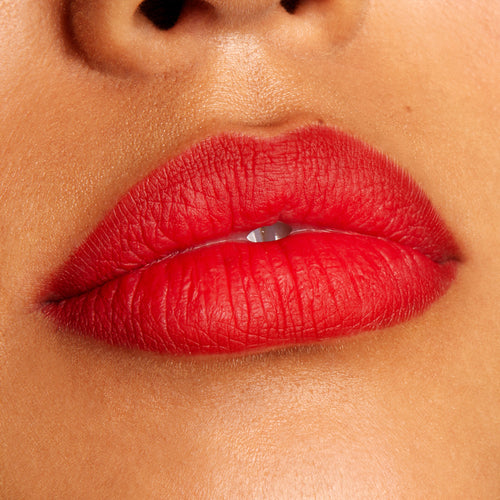 Lips wearing Overtime, a ColourPop Lippie Pencil, lining and filling the mouth in a vivid true red with a soft matte finish; close-up beauty shot highlights crisp edges and even color payoff on warm-toned skin.