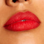 Lips wearing Overtime, a ColourPop Lippie Pencil, lining and filling the mouth in a vivid true red with a soft matte finish; close-up beauty shot highlights crisp edges and even color payoff on warm-toned skin.