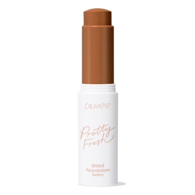ColourPop Pretty Fresh Tinted Foundation Balm, shade Dark 20, stands uncapped with the twist-up stick exposed in a deep warm brown, housed in a white tube labeled Pretty Fresh against a clean white background.