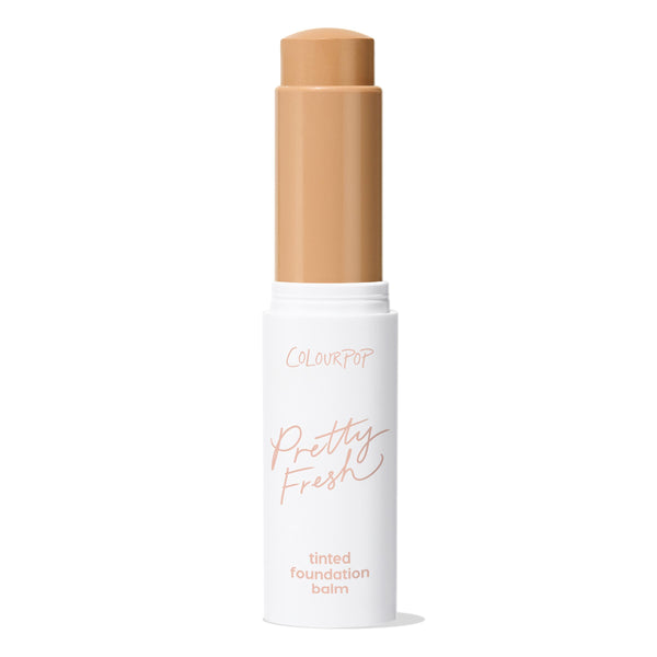 ColourPop Pretty Fresh Tinted Foundation Balm in Medium Dark 13 twists up from a white tube with blush pink “Pretty Fresh” script, cap removed, revealing a medium-dark tan balm stick against a plain white background.