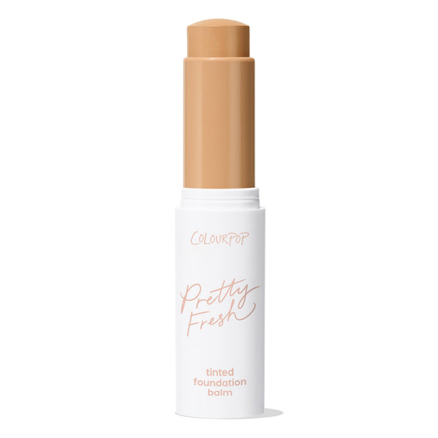 ColourPop Pretty Fresh Tinted Foundation Balm in Medium Dark 13 twists up from a white tube with blush pink “Pretty Fresh” script, cap removed, revealing a medium-dark tan balm stick against a plain white background.