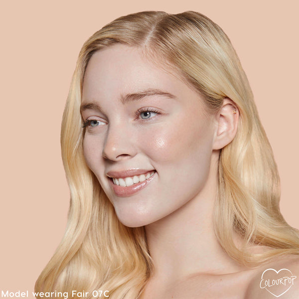 Fair 07 C shade brightening a model’s complexion with smooth, dewy medium coverage from the ColourPop Pretty Fresh Creamy Concealer, shown in a close-up against a peach backdrop to showcase even tone around eyes and cheeks.