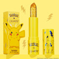 Thunderbolt transforming ColourPop pH Lip Balm bullet sparkles with gold flecks, standing uncapped between its Pikachu-printed yellow tube and matching box on a bright yellow backdrop with lightning accents, 3.5 g/0.12 oz.