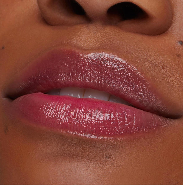 Glossy lips wearing Transform pH Lip Balm reveal a color-changing rosy pink tint and hydrated shine in a close-up lip swatch, showcasing the smooth, cushiony finish of the ColourPop pH Lip Balm.