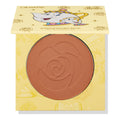 Chip ColourPop Pressed Powder Blush compact - half-open to show a warm rosy terracotta pan embossed with a rose - rests in yellow Disney Beauty and the Beast packaging featuring Mrs. Potts and Chip illustrations and gold rose motifs.