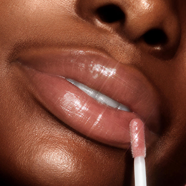 Full, glossy lips apply Dream Duo, a ColourPop Ultra Lip Duo, with a doe-foot applicator, showcasing a nude-pink, high-shine finish in an extreme close-up studio shot.