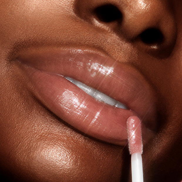 Full, glossy lips apply Dream Duo, a ColourPop Ultra Lip Duo, with a doe-foot applicator, showcasing a nude-pink, high-shine finish in an extreme close-up studio shot.
