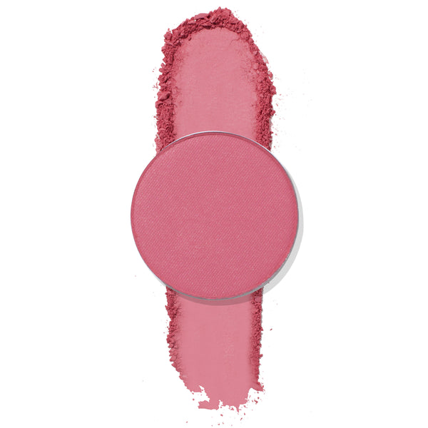 ColourPop Poodle pressed powder eyeshadow, a round single pan in matte rosy pink, sits atop a vertical swatch with soft crumbled edges, showcasing smooth, blendable pigment on a clean white background.