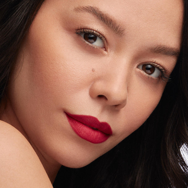 Bold red lips wear I Heart This ColourPop Lippie Pencil, lining and filling with a vivid matte red; close-up beauty shot shows smooth skin, soft gold eye makeup, and studio lighting highlighting crisp edges and saturated color.