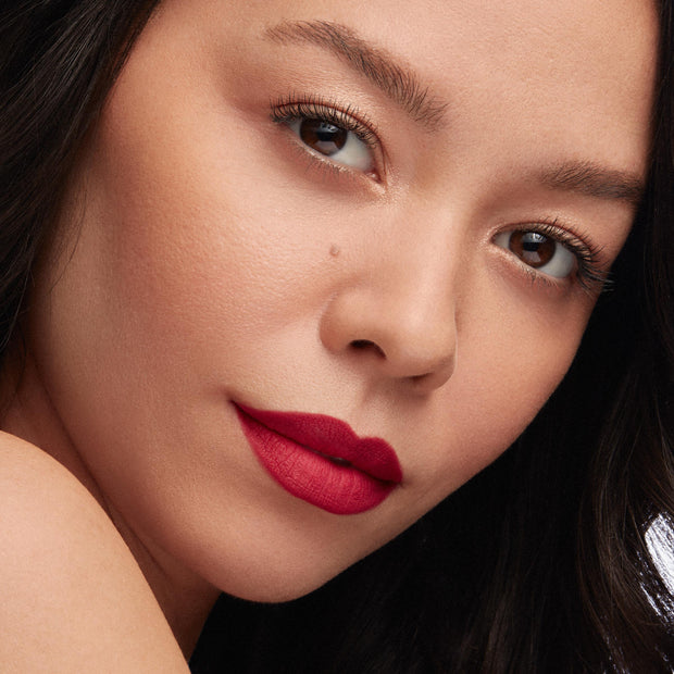 Bold red lips wear I Heart This ColourPop Lippie Pencil, lining and filling with a vivid matte red; close-up beauty shot shows smooth skin, soft gold eye makeup, and studio lighting highlighting crisp edges and saturated color.