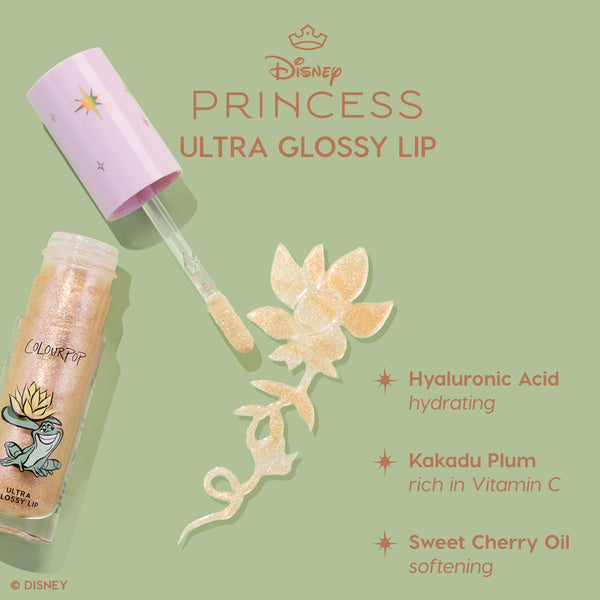 Colourpop Disney Princess Ultra Glossy Lip tube with wand swiping shimmery gold gloss in a floral swirl on a green background, highlighting hyaluronic acid hydration, Kakadu plum vitamin C, and sweet cherry oil softening benefits.