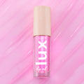 ColourPop Lux Lip Oil in Raspberry Mojito, a clear tube with bold “LUX” lettering and a beige star-print cap, displayed on a glossy swirled pink background, showcasing the vibrant pink-tinted lip oil formula.