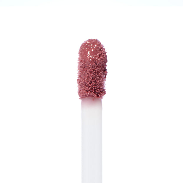 Doe-foot applicator swiping Rose Latte Ultra Blotted Lip, a rosy mauve-brown shade with a soft blurred finish, against a white background; ColourPop Ultra Blotted Lip macro highlighting plush bristles and creamy texture.