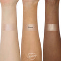 ColourPop Super Shock Highlighter in Ohana swatched in wide stripes on three forearms (light, medium, deep), revealing a pink champagne shimmer with smooth, high-shine payoff; center swatch labeled OHANA on a clean white studio background.