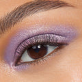 Shimmering lavender-pink eyelid wearing Rose Garden, a ColourPop Super Shock Shadow, blended across lid and lower lash line with metallic sheen and fine sparkle, accenting a brown eye and soft lashes in a tight close-up beauty shot.