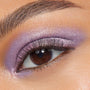 Shimmering lavender-pink eyelid wearing Rose Garden, a ColourPop Super Shock Shadow, blended across lid and lower lash line with metallic sheen and fine sparkle, accenting a brown eye and soft lashes in a tight close-up beauty shot.