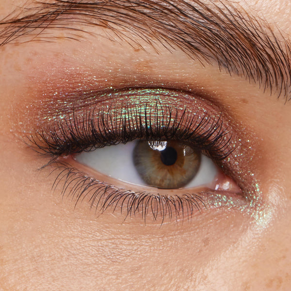 Shimmer-dusted eyelid wears Rooftop Cocktails, a rose-to-mint duochrome from the ColourPop Super Shock Shadow line, catching light across the lid while defined lashes frame the eye in a tight beauty close-up.