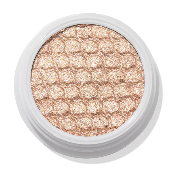 ColourPop Sailor Super Shock Shadow glitters in a close-up, a champagne-beige cream eyeshadow with a honeycomb quilted texture, seated in a white round pot on a clean white background, showcasing its metallic shimmer finish.