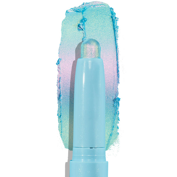 Colourpop Game Over Shadow Stix eye crayon gliding across a white background, leaving a bold metallic aqua, lavender, and mint duochrome shimmer swatch behind its pastel blue twist-up tube packaging.